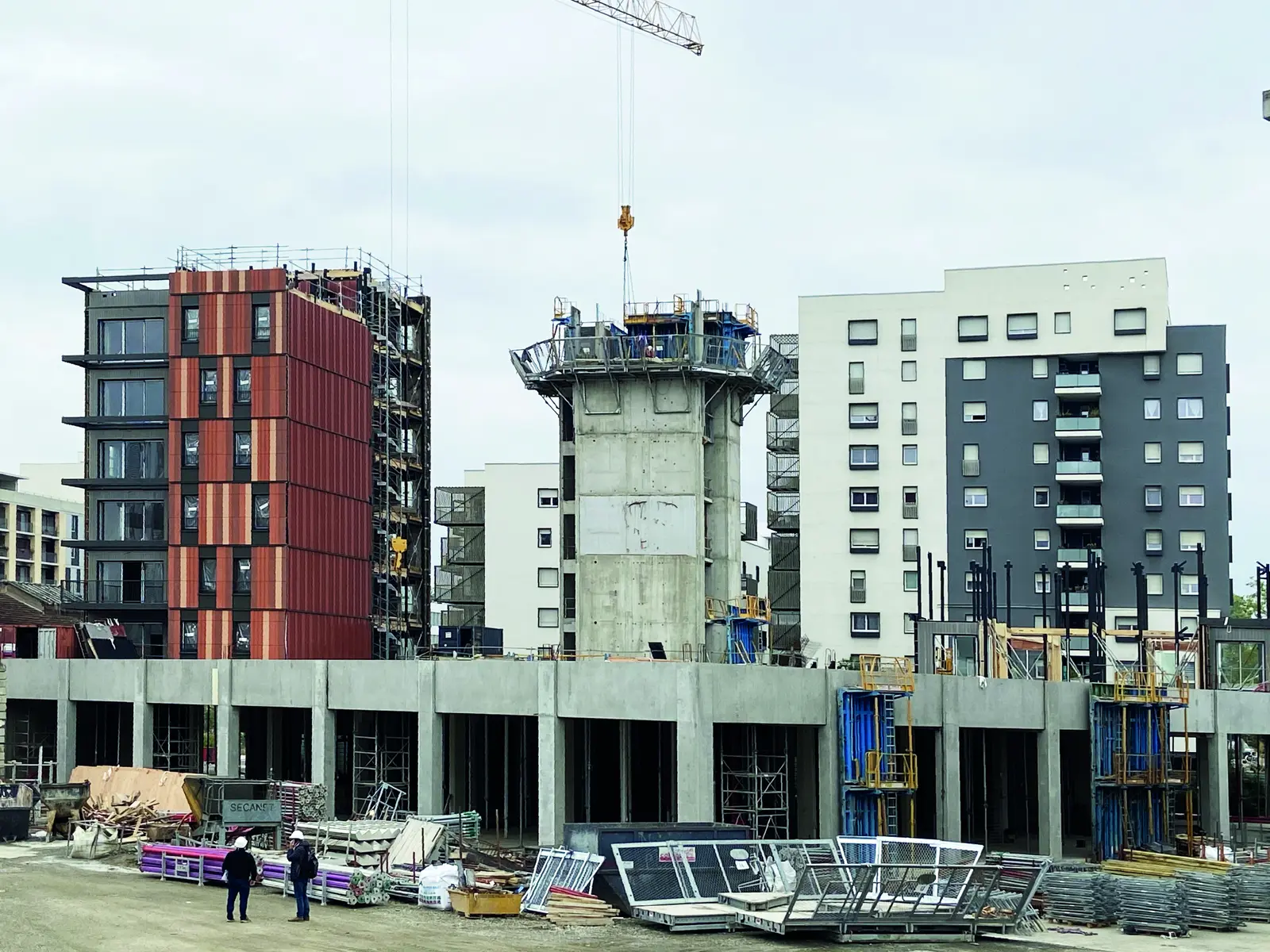 Chantier Wood Art avec un b&acirc;timent &agrave; bardage rouge, un noyau en b&eacute;ton et une grue
