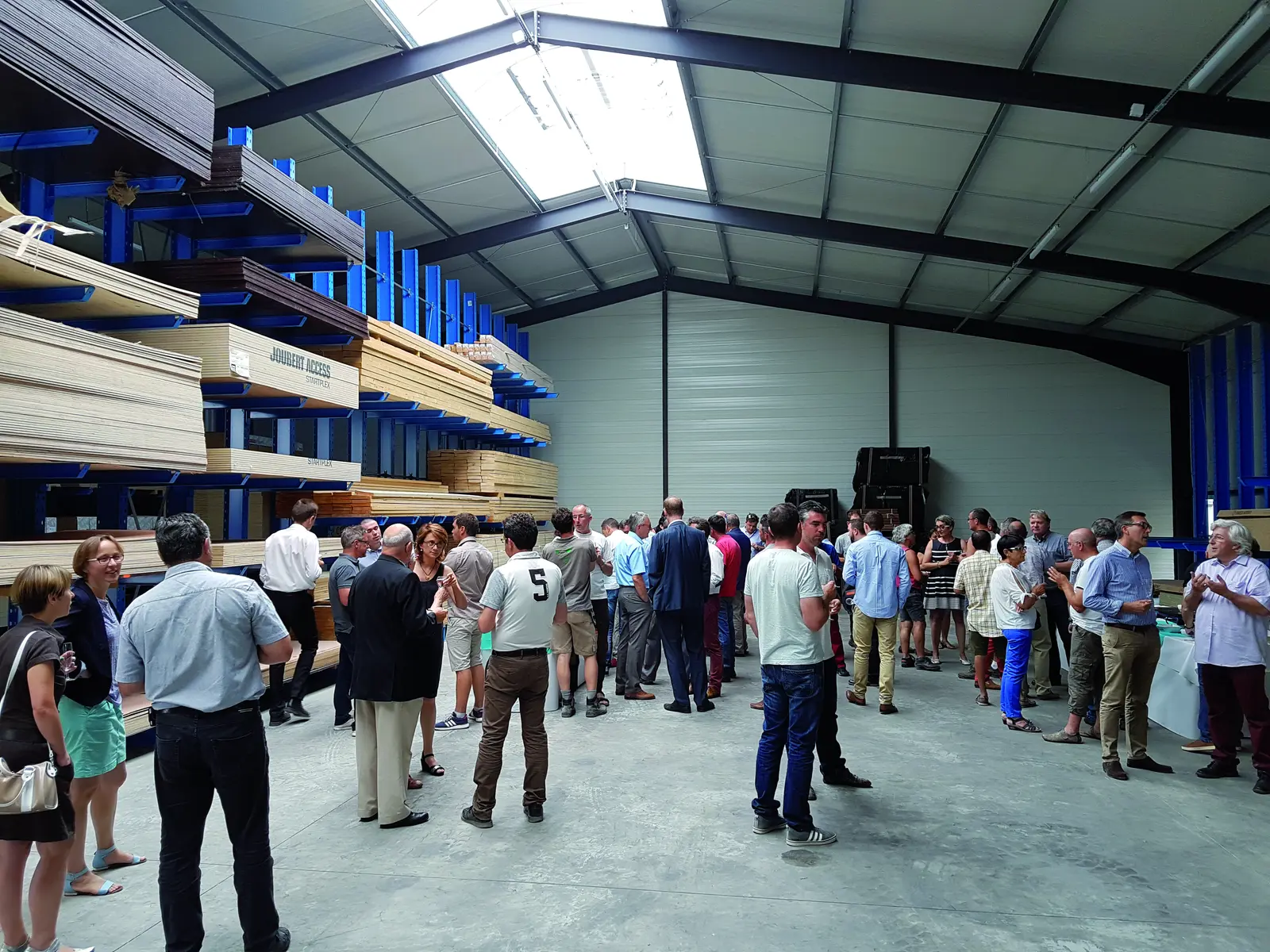 Les invités dans le nouveau bâtiment de négoce, devant les rayonnages de bois