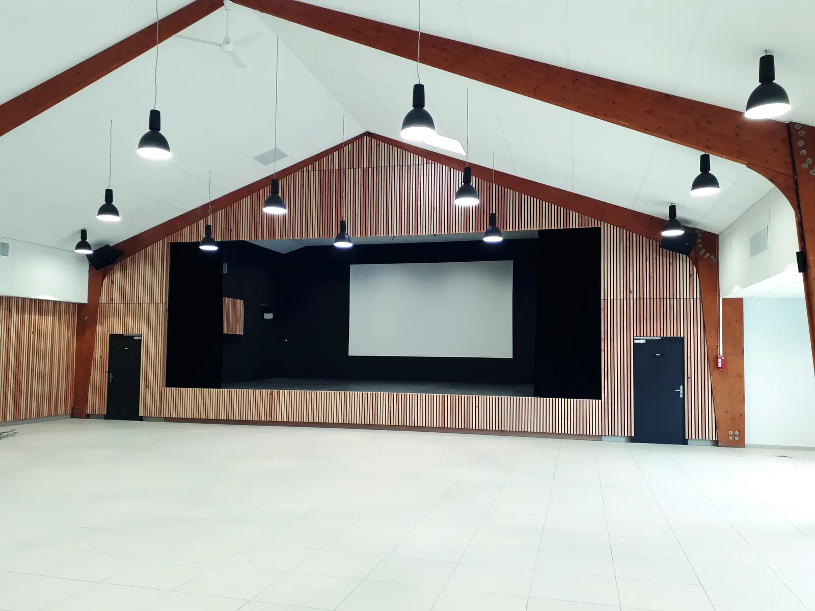 Sc&egrave;ne de la salle des f&ecirc;tes de Bois-de-Haye encadr&eacute;e de parements muraux en bois &agrave; claire-voie