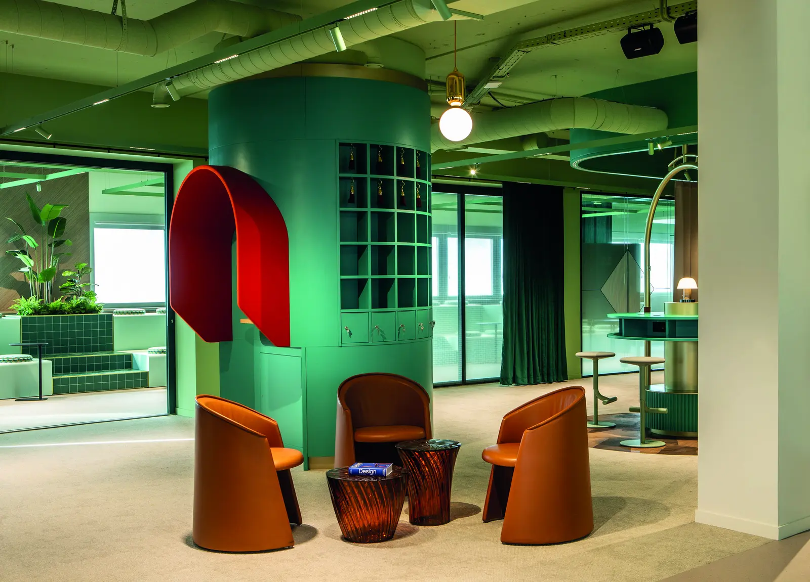 Espace lounge avec volume vert, arche rouge et fauteuils cuivrés