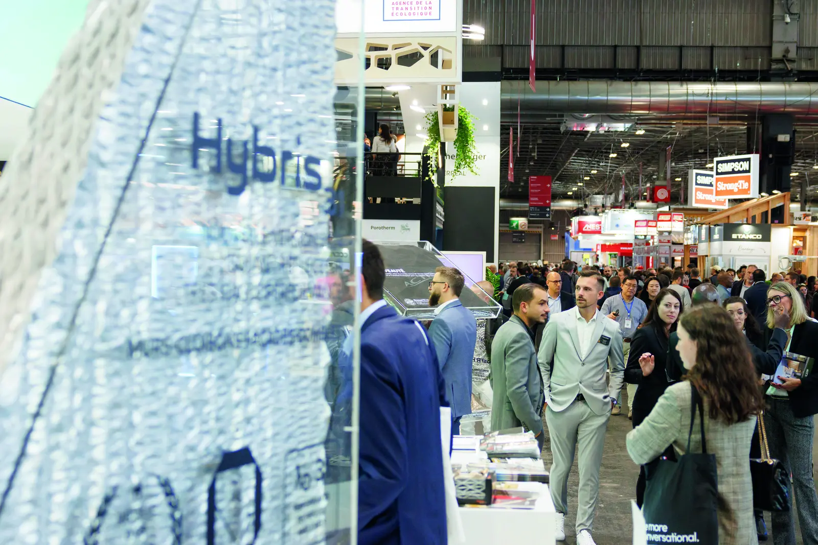 Visiteurs dans les allées du salon, devant un stand d’isolant