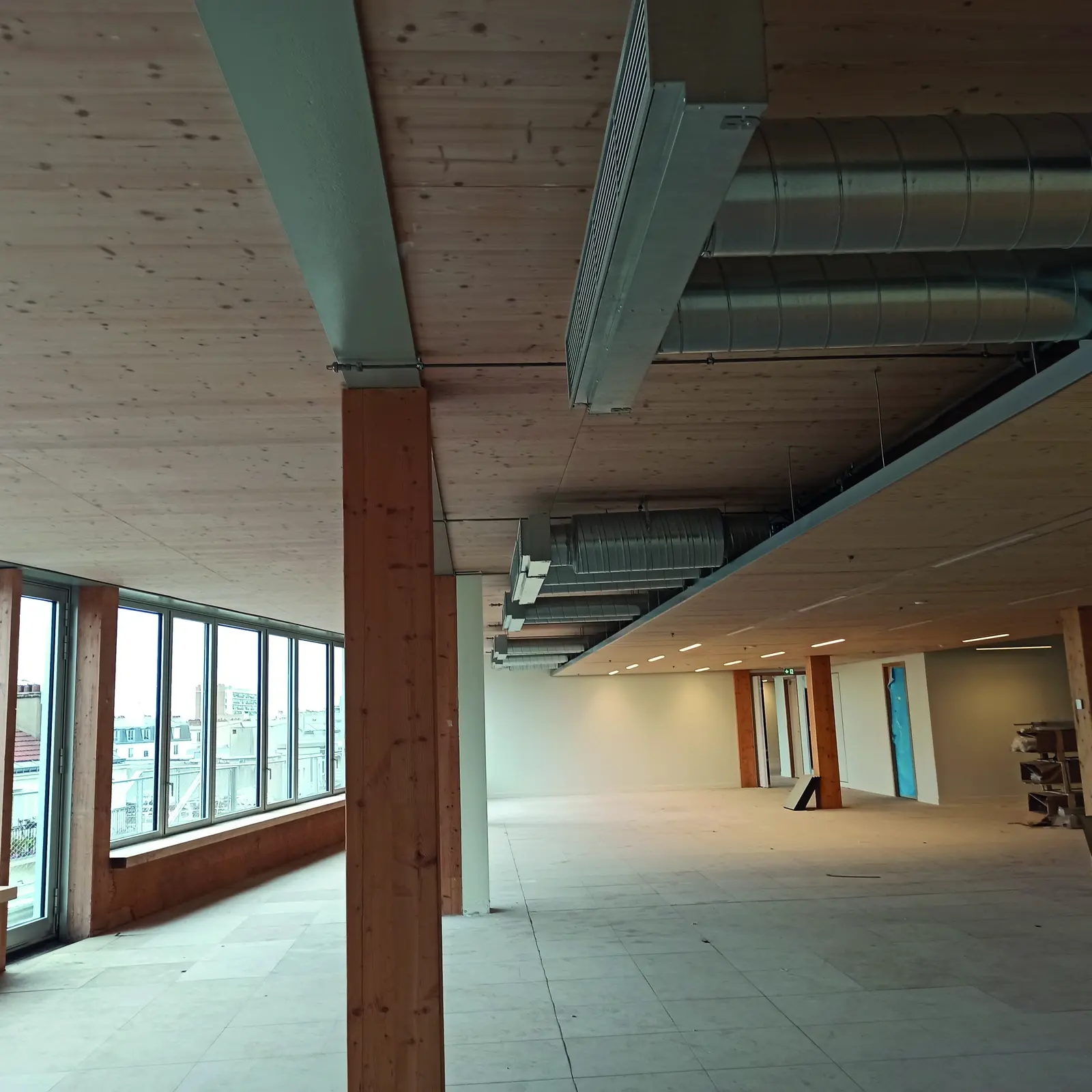 Plateau de bureaux en chantier avec poteau en lamell&eacute;-coll&eacute;, plafond en CLT et grandes baies vitr&eacute;es