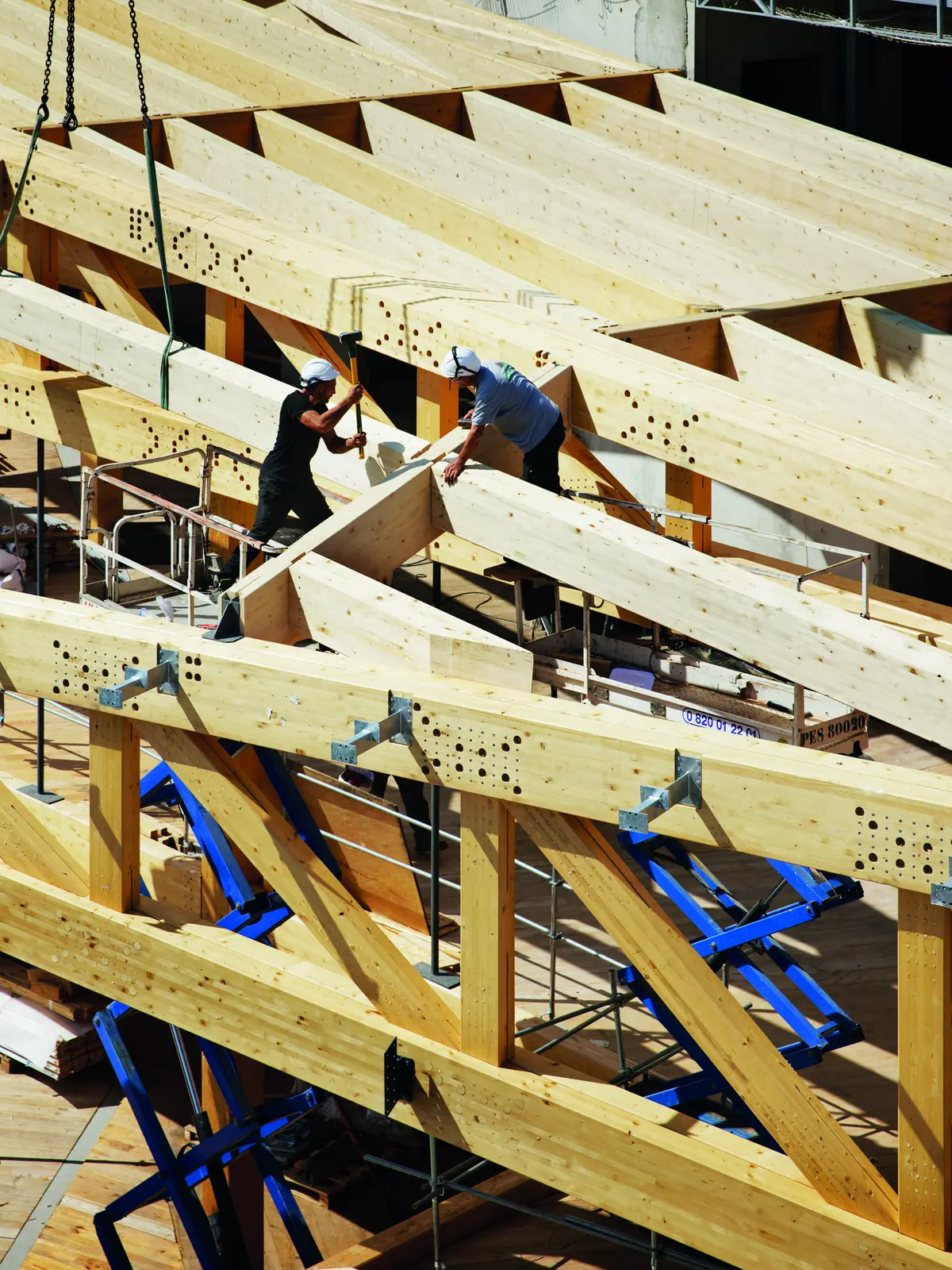 Charpentiers assemblant des poutres treillis en bois sur le chantier