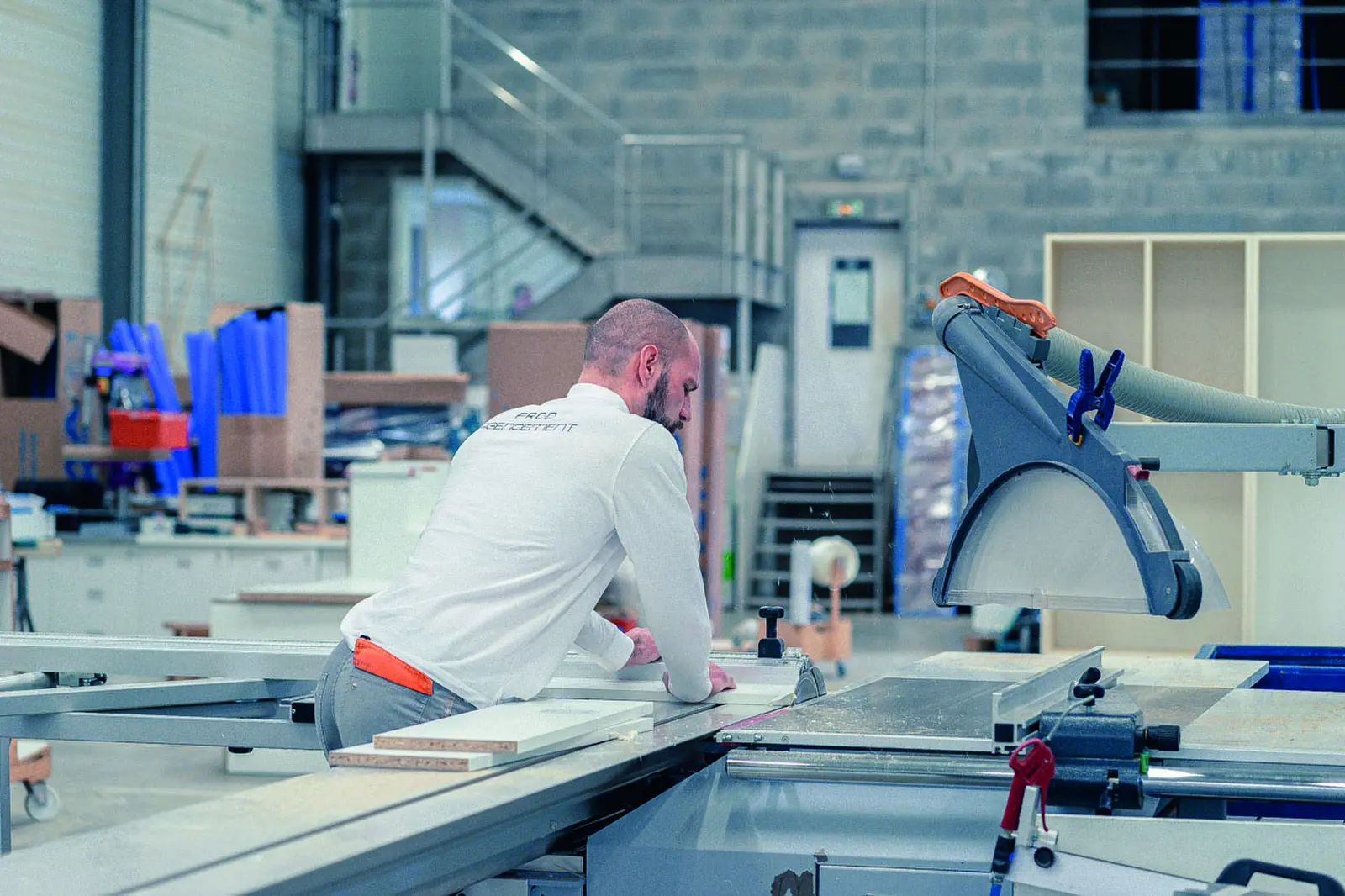 Opérateur de dos devant les machines d’un atelier d’agencement