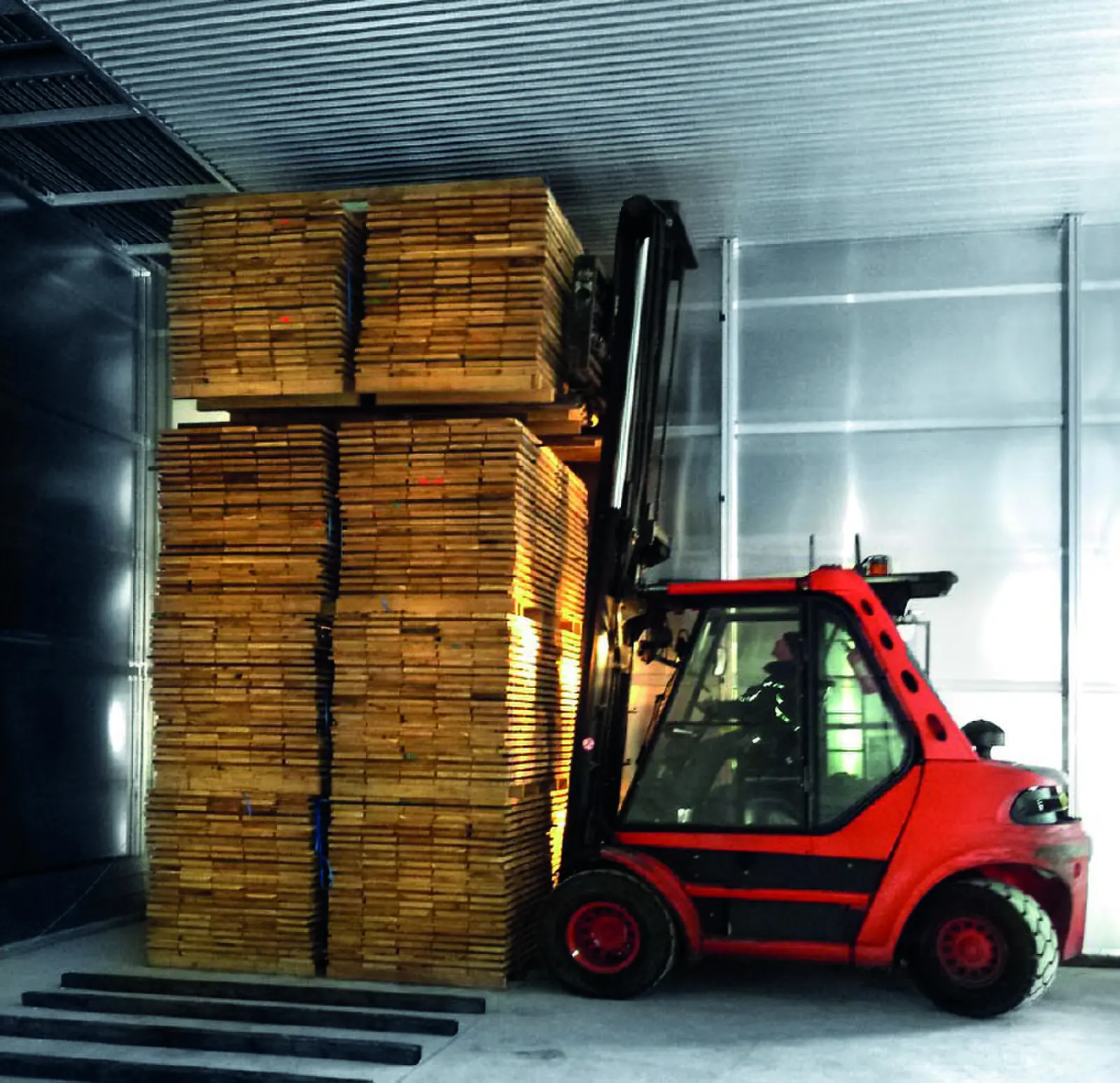 Chariot &eacute;l&eacute;vateur chargeant des paquets de bois dans le pr&eacute;s&eacute;choir