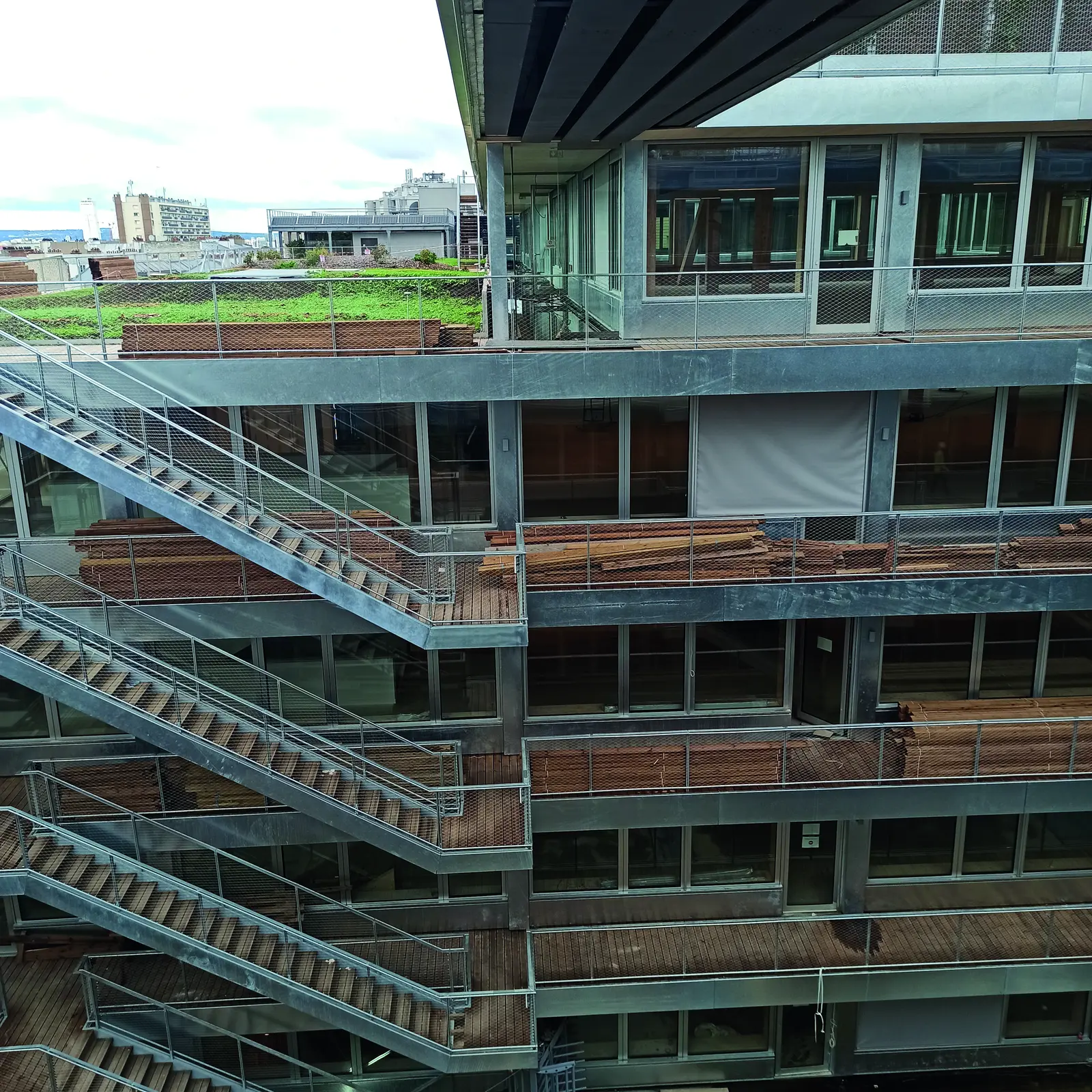 Escaliers ext&eacute;rieurs et coursives m&eacute;talliques sur la fa&ccedil;ade du patio, toiture v&eacute;g&eacute;talis&eacute;e en arri&egrave;re-plan
