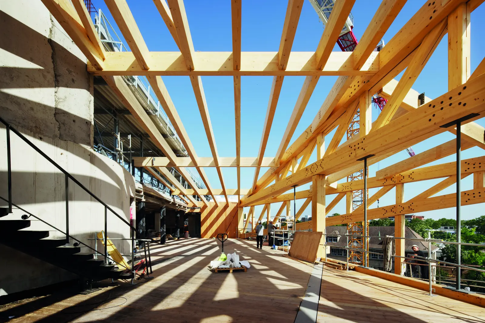 Charpente en bois en cours de montage sur un plateau du chantier, sous le ciel