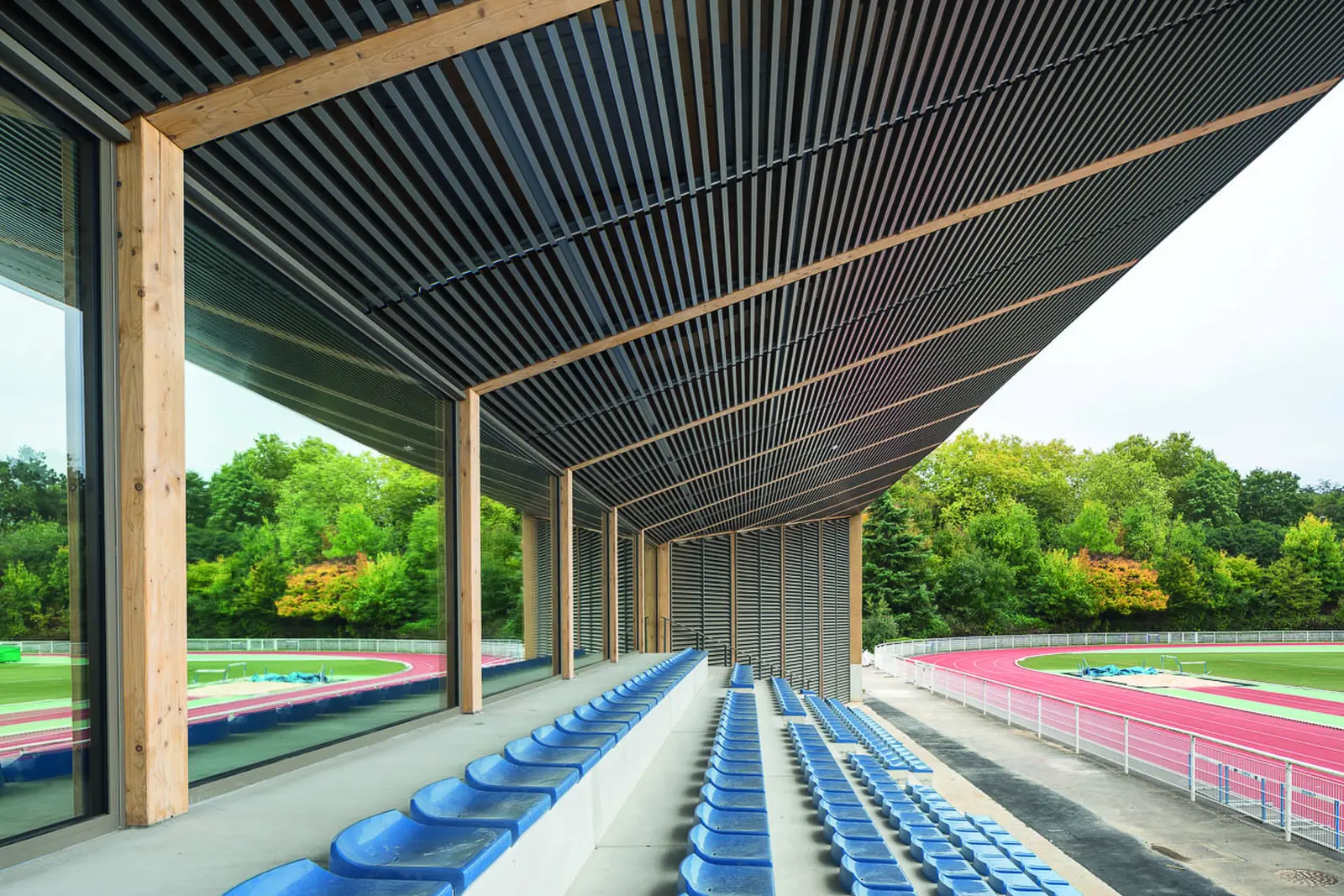 Tribune sportive couverte d&rsquo;une charpente bois face &agrave; la piste d&rsquo;athl&eacute;tisme
