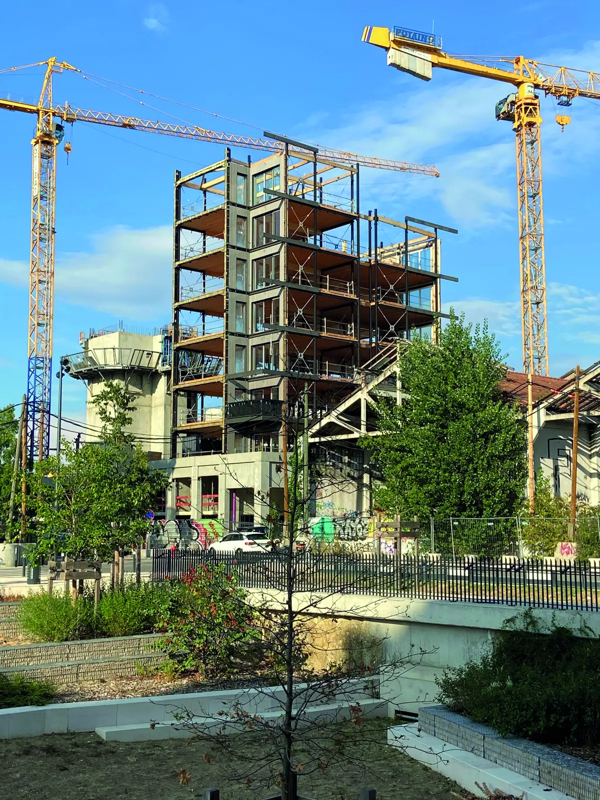 Ossature en bois et m&eacute;tal d&rsquo;un immeuble en construction entre deux grues