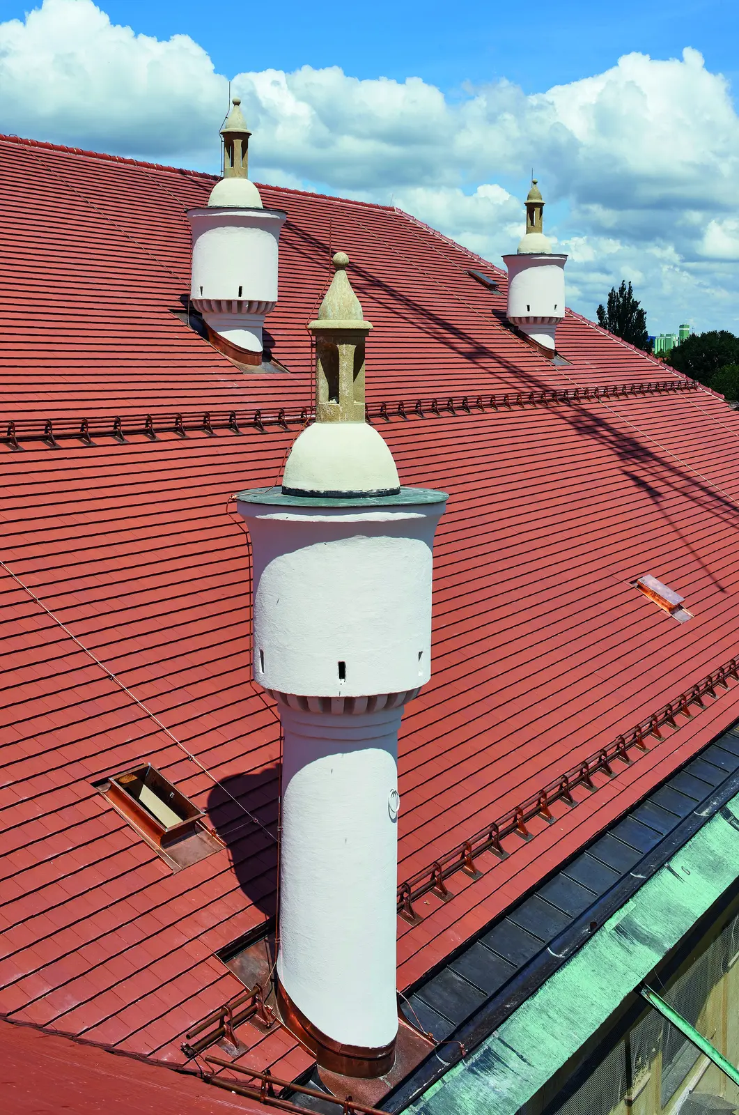 Toiture en tuiles plates Erlus et cheminées rondes blanches du palais