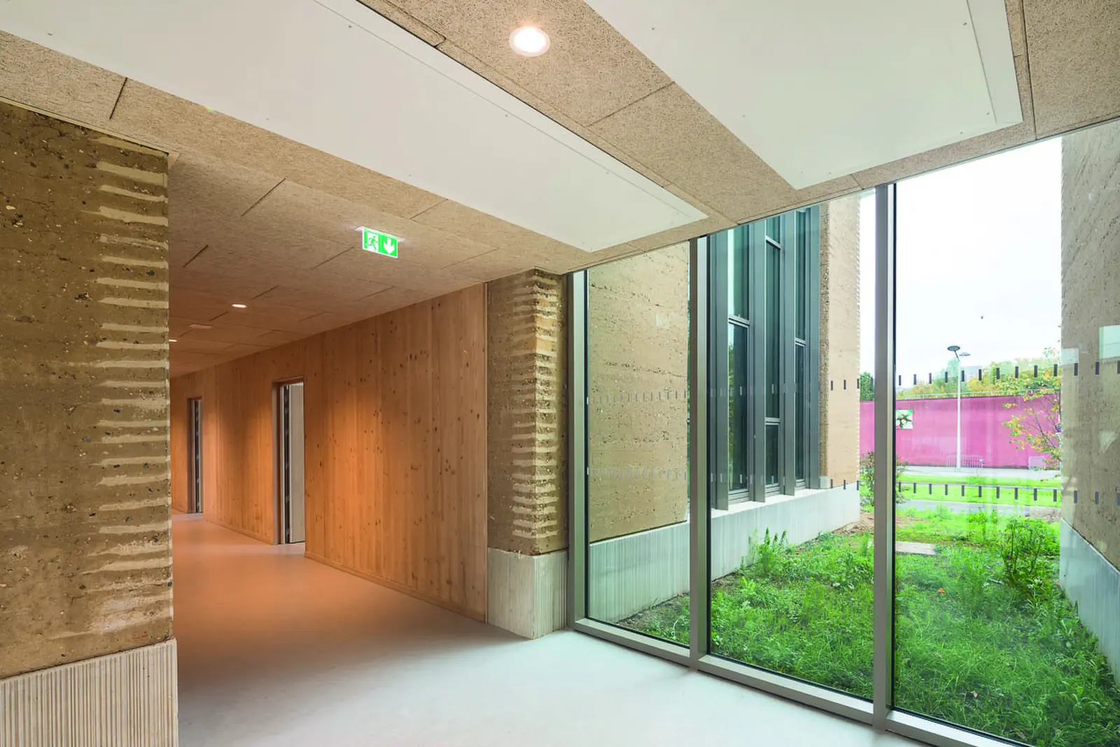 Couloir int&eacute;rieur entre mur en pis&eacute; et fa&ccedil;ade vitr&eacute;e